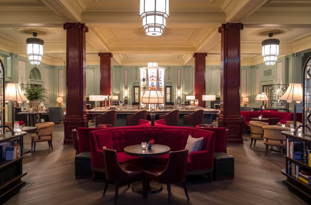 El interior del Century Bar en Gleneagles Hotel con un bar de isla rodeado de banquetas rojas