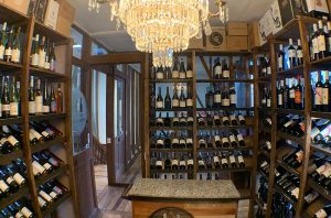 Estantes de botellas de vino en una tienda de vinos con un candelabro en el techo